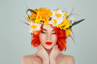 Modeli ile gülümseyen güzel genç kadın baş çiçek kafa bandı saç makyaj üzerine beyaz sarı çiçekler ve yeşil göz farı ışık yeşil gri arka plan üzerinde izole gözler kapalı. Bahar kadın kavramı