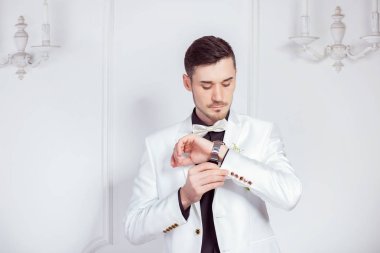 Zarif lüks yakışıklı modern Damat takım elbise giyen kol saati ve beyaz arka plan üzerinde duran 