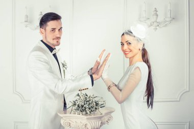 Zarif genç adam ve kadın düğün yan görünüm birbirimizi kameraya bakarak önünde dururken yığın el kıyafetler