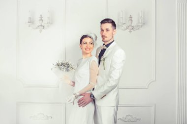 İçerik gelin ve damat kucaklama beyaz arka plan üzerinde ayakta moda düğün giysileri giyiyor