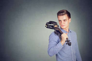 Çağdaş keman uzakta gri arka plan üzerinde seyir omuz üzerinde tutarak tişörtlü yakışıklı adam