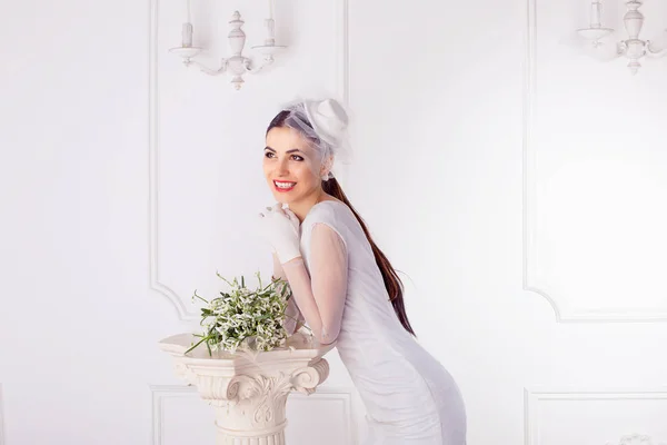 Красивая Брюнетка Элегантном Свадебном Платье Шляпе Завесой Опираясь Колонну Цветами — стоковое фото