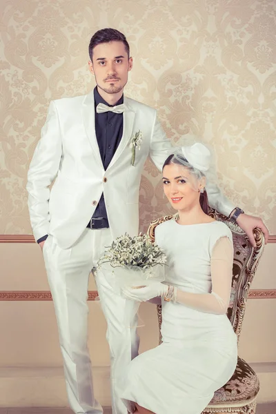 Şık zarif damat yakın duran ile iskemlede buket gelinle