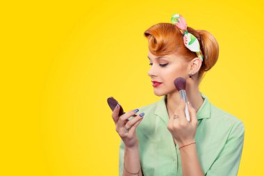 Yukarı, yukarı yapmak düzeltme dokunmadan. Closeup kırmızı kafa genç kadın oldukça pinup kız yeşil düğme gömlek holding ayna izole sarı arka plana retro vintage görünümlü allık toz kullanarak 50 's stil.