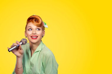 Şarkıcı. Hayalifener sarı arka plan duvar boşaltmak olumlu yüz ifadesi seyir gülümseyen mikrofon ile şarkı söyleyen Bayan pinup 50s kız seksi güzel mutlu genç kadın portre portre kafa vurdu