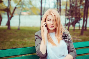 Şüpheci kadın cep telefonunda söz. Portre bir tezgah şehir kentsel park arka plan üzerinde oturan konuşma ile mutsuz ciddi iş kadını memnun üzgün. Negatif duygu yüz ifadesi