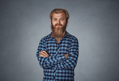 Genç adam katlanmış sen kamera boyuyla bakan sakallı. Mavi Kareli sakallı hippi erkek gömlek Isolated gri studio arka plan üzerinde kareli. Negatif yüz ifadesi, insan duygu, beden dili