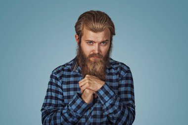 Portre genç adam hoş olmayan garip durum endişeyle eli ile oynar. Mavi Kareli sakallı hippi erkek forması mavi stüdyo arka plan Isolated damalı. Negatif yüz ifadesi.