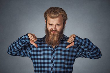 Başparmak aşağı serin sakallı adam. Mavi Kareli sakallı hippi erkek gömlek Isolated gri studio arka plan üzerinde kareli. Negatif yüz ifadesi, insan duygu, beden dili, tepki, tutum