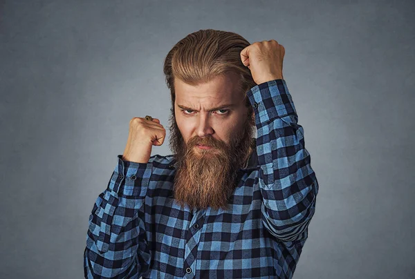 Confident sporty boxing man holding fists in front of him, going to fight and defend himself, ready for fighting. Hipster man with beard in blue plaid checkered shirt  Isolated on gray Background.