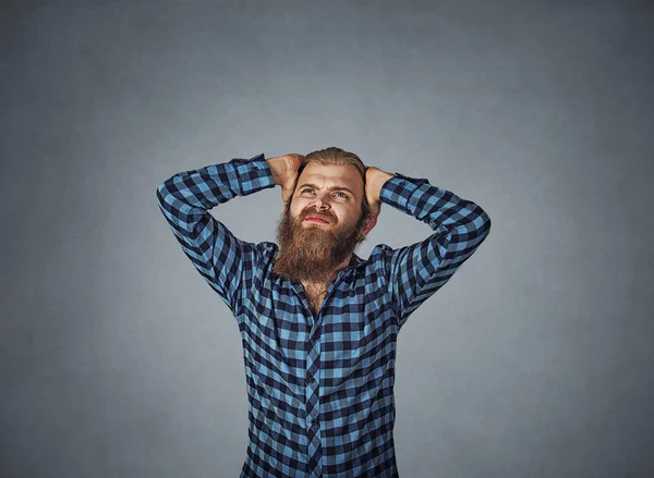 Furious angry mad man screaming looking up hold hand on head, young frustrated and stressed guy, concept of male yelling, problem crisis. Hipster man with beard in blue plaid checkered shirt  on gray.