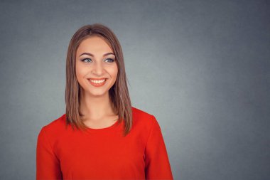 Tarafına bakarak mutlu gülmek gülümseyen güzel ve genç birbayan. İş kadını kırmızı elbiseli bob saç modeli. Arka plan gri gri stüdyo duvarda izole. Negatif yüz ifadesi, insani duyguları.