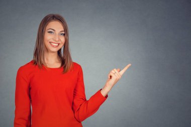 Kopya alanı ürün veya metin için parmağınızla işaret gösteren gülümseyen genç kadın. İş kadını kırmızı elbiseli bob saç modeli. Arka plan gri gri stüdyo duvarda izole. Pozitif yüz ifadesi.