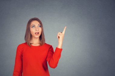 Açık ağız gri studio duvar arka plan üzerinde izole boşaltmak için işaret sürpriz kadınla. Rahat kıyafetler parmağıyla yukarıyı çekici kız. İş kadını kırmızı elbiseli bob saç modeli. 