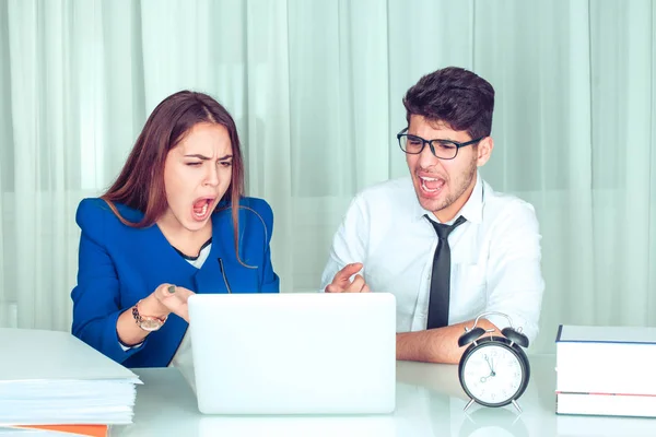 Stressed angry business woman and man with laptop looking at it sitting at table screaming at computer. Negative emotions in office life. Problems at work concept. Negative face expressions, emotions.