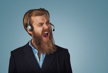 Genç Yetişkin hipster kulaklık çalışma operatör rahatsız olarak, öfke, deli ve bağırıyor, kızgın müşteri hizmeti temsilcisi kavramı mavi arka plan ile sinirli bağıran adamla. Negatif yüz