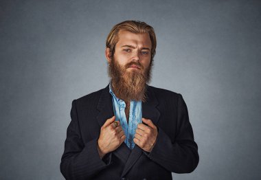 Kendine güvenen sakallı hippi işadamı ayakta seyir siyah tutan kollarını seninle, düz ceket gri gri stüdyo duvar arka plan göl kenarında uygun. Pozitif yüz ifadesi, insani duyguları.