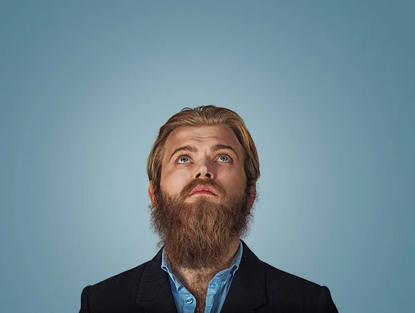 Head shot confused serious hipster business man thinking looking up thoughtful isolated on gray grey wall background with copy space above head. Human face expressions, emotions feelings body language