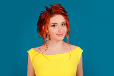 Genç güzel sevimli neşeli kız kamera hafif gülüşe seyir gülümseyen portresi yüz beyaz kişi sarı elbiseli ve üzerinde mavi stüdyo arka plan bej ruj, Kızıl saç izole.