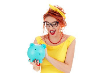 Genç bir kumbara euphoric bakıp hayret tutan kadın hayrete heyecanlı. Beyaz kişi sarı elbise ve beyaz stüdyo arka plan üzerinde izole kırmızı ruj Kızıl saçlı mercan kolye