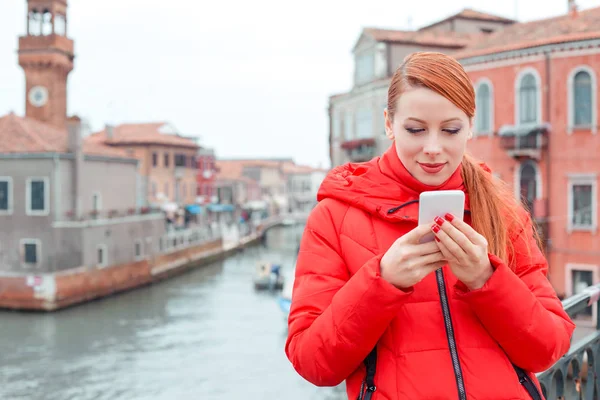 Cute smiling Latina woman using smart phone in Venice Italy