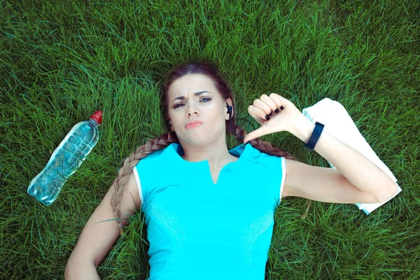 woman giving thumb down hands gesture lying down on meadow