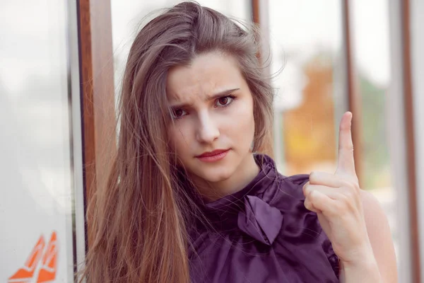 Attention, listen to me. Close up portrait of young woman wagging her finger isolated outside city salon store wall background. Negative human emotions face expression, feelings body language attitude