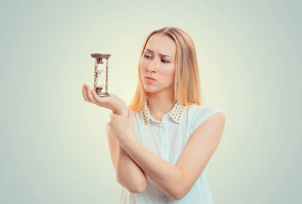Upset gloomy woman looking at hourglass — Stock Photo, Image