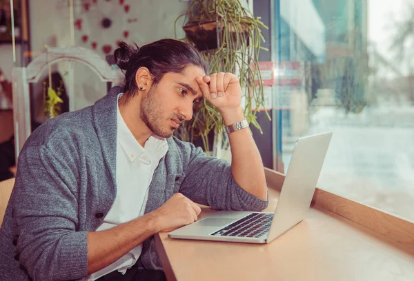 Frustrierter Mann mit Hand auf dem Kopf blickt besorgt auf Laptop — Stockfoto