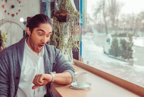 Shocked man looking to wristwatch for time, being late