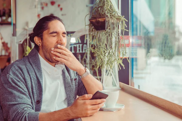 Hombre gracioso soñoliento, bostezar la boca mirando el teléfono inteligente aburrido por la conversación telefónica, mensajes de texto — Foto de Stock