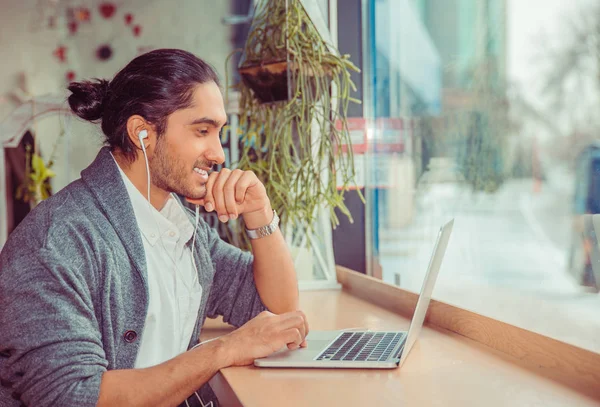 Чоловік в навушниках дивиться на комп'ютер усміхнений щасливий — стокове фото