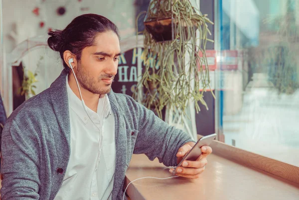 Homem infeliz com fones de ouvido olhando para um telefone celular — Fotografia de Stock