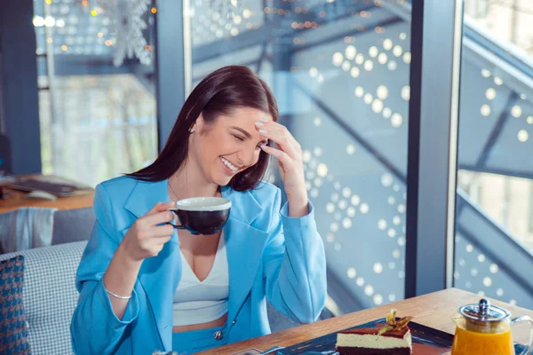 beautiful woman holding a cup of hot beverage laughing