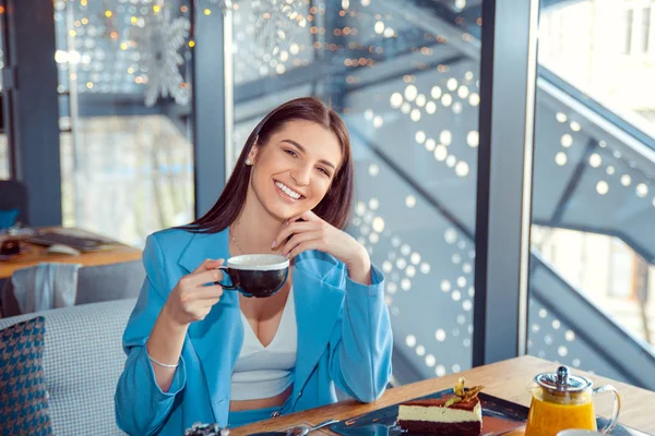Женщина сидит на балконе кафе держа чашку горячего чая . — стоковое фото