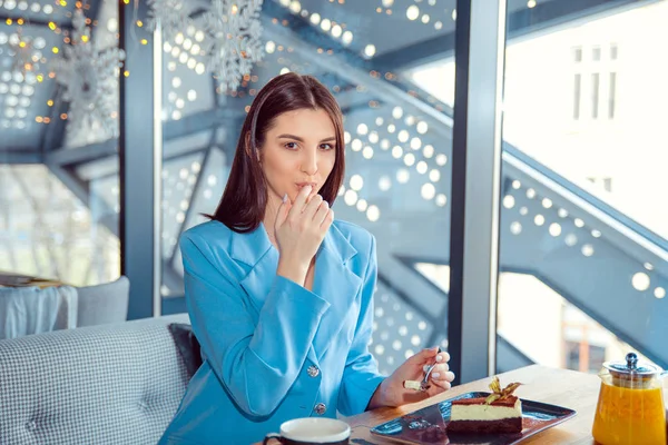 Mujer disfrutando de pastel de postre mientras está sentado en la cafetería . —  Fotos de Stock