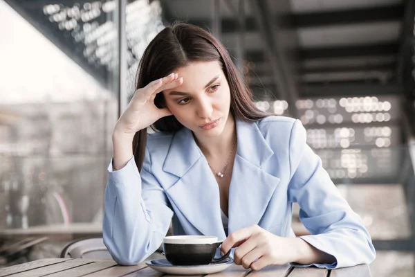 Mujer triste en un café sosteniendo la cabeza con la mano . — Foto de Stock
