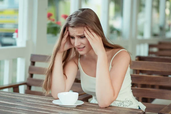 sad young woman with coffee cup sitting on a trendy cafe