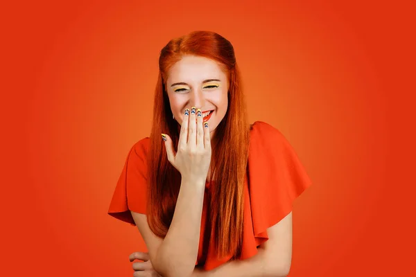 Happy woman laughs and covers her mouth with hand