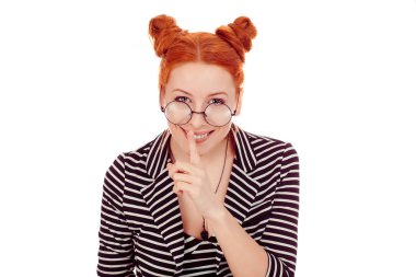 Gülümseyen bir kadın gizlilik istiyor. Parmağı dudakta. El hareketi, beyaz arka plan duvarında izole edilmiş. Güzel bir kız parmaklarını dudaklarına 