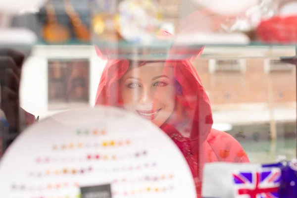 Side profile woman smiling looking at bijouterie in the shop window in Italy Murano Island. Lady in red winter coat clothing redhead hair standing on urban background. Big choice of jewelry concept