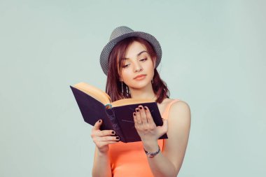 Ciddi bir kadın elinde kara kaplı bir kitapla ilgileniyordu. Gri şapkalı, açık yeşil renkli stüdyo arka planında not defteri olan genç hippi kız ilgileniyordu.. 