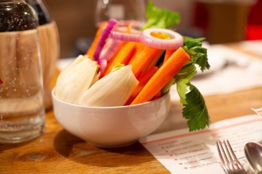 Vegan Buda kasesi. Taze çiğ sebzeli kase - turp, havuç, ognion, turp, beyaz seramik tabakta yeşil maydanoz ve ahşap bir masa. Otel kahvaltısı. Seçici odak