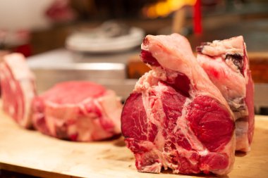 Ahşap masa mutfağında çiğ sığır kaburgası bifteği. Arka plan olarak, kapalı alanda.