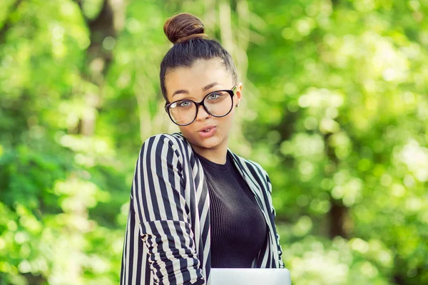 眼鏡をかけた若い魅力的な女の子 緑の自然を背景に 屋外の都市公園で ラップトップを持つ女性 フリーランスのビジネスコンセプト 面白い感情表情 — ストック写真