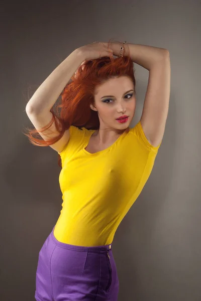 Woman looking at you camera happily, redhead girl posing looking cheerful looking to you isolated on light beige studio wall background. Positive face expression, human emotion