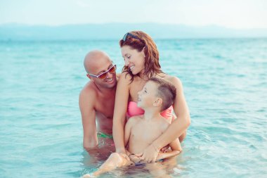 Mutlu, genç bir aile, tatillerde denizde, güzel plajlarda, açık havada eğleniyor.