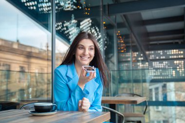 Telefonun ses tanıma özelliğini kullanan bir kadının portresi Manhattan New York 'ta ya da evinin balkonunda lüks bir kafede oturuyor.