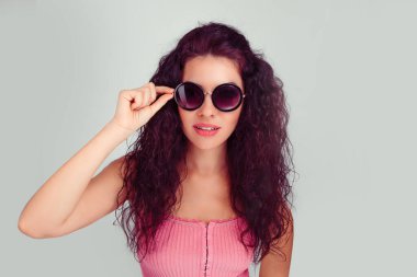 Kendine güvenen güzel, çekici bir genç kızın yakın plan portresi. Güneş gözlüğü takan bir moda kızı. Açık yeşil arka plan.