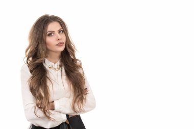 Yakından çekilmiş portre, şüpheci, ciddi bir genç kadın şüpheli görünüyor, yüzü onaylanmamış, kolları kavuşturulmuş, izole edilmiş beyaz bir arka plan. Negatif insani duygular, yüz ifadeleri, duygular